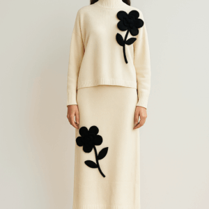 CONJUNTO DE PUNTO BLANCO DE JERSEY CUELLO PERKINS Y FALDA MIDI CON DETALLE DE FLOR NEGRA EN RELIEVE EN LA PARTE IZQUIERDA DEL JERSEY EN LA PARTE DERECHA DE LA FALDA